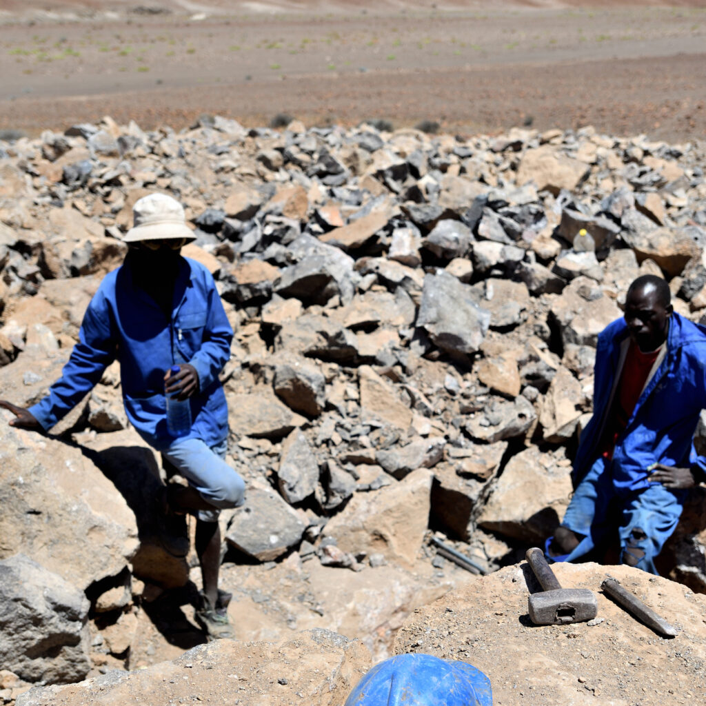 two gobogobos miners with hardhat, working mineral seam near brandberg mountain, namibia